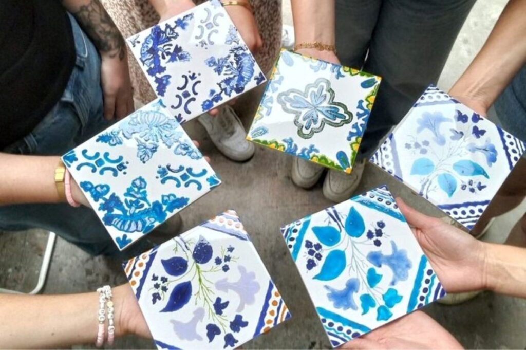 Team sharing their tiles after painting traditional azulejo with a local artisan