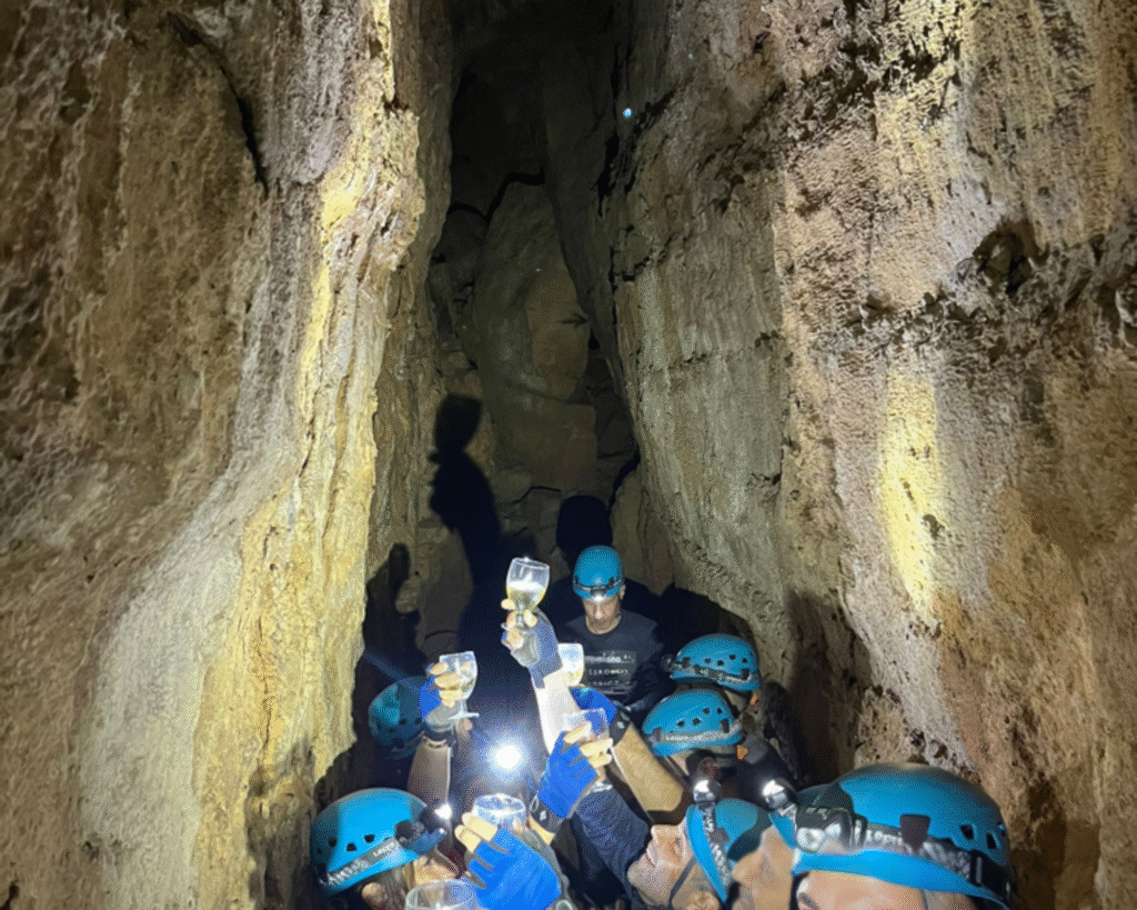 Executive team building Barcelona: senior leaders in helmets and gloves celebrating inside a tectonic cave after completing the leadership challenge