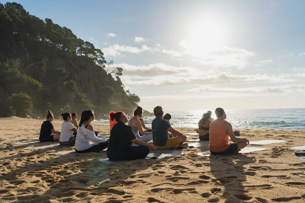 Group morning yoga session on a Spanish beach as part of a corporate wellness event